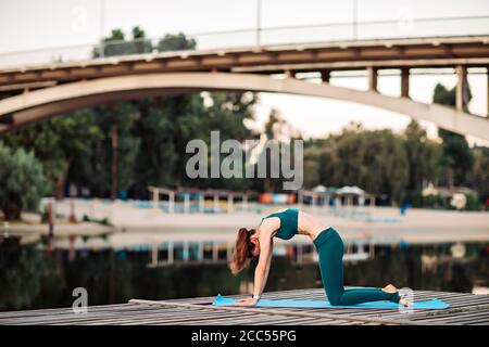 Sport donna fare yoga su piattaforma di legno Foto Stock