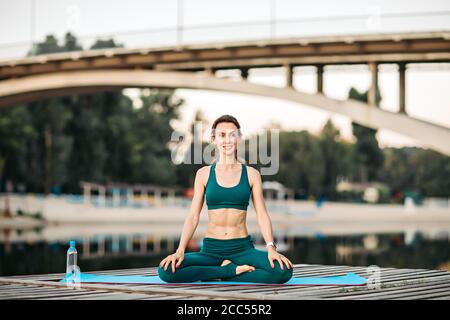 Sport donna fare yoga su piattaforma di legno Foto Stock