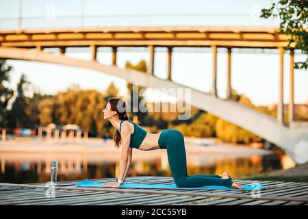 Sport donna fare yoga su piattaforma di legno Foto Stock
