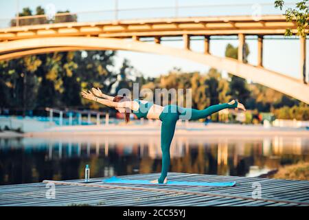 Sport donna fare yoga su piattaforma di legno Foto Stock