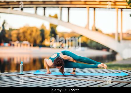 Sport donna fare yoga su piattaforma di legno Foto Stock