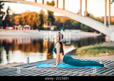 Sport donna fare yoga su piattaforma di legno Foto Stock