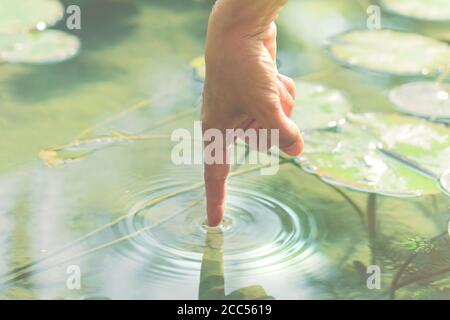 la persona tocca l'acqua con la mano Foto Stock