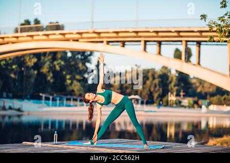 Sport donna fare yoga su piattaforma di legno Foto Stock