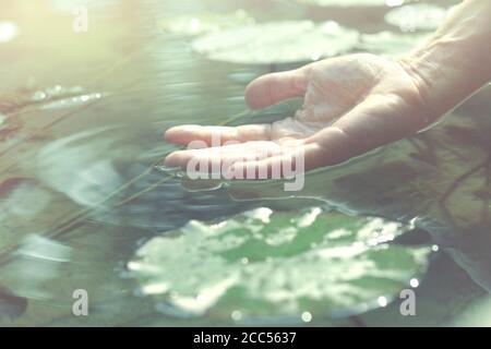 la persona tocca l'acqua con la mano Foto Stock