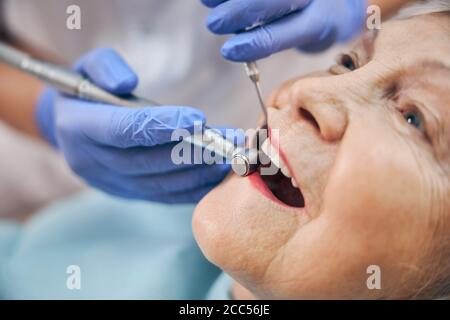 mani di medico in guanti blu utilizzando il trapano durante il trattamento denti Foto Stock