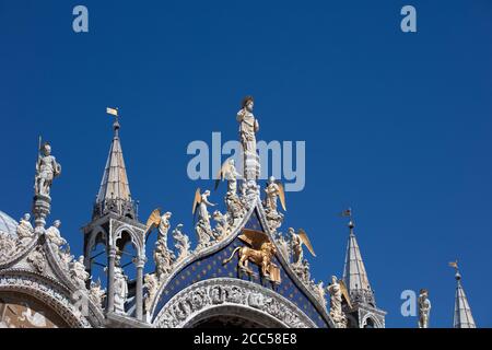 Particolare della statua centrale di cristo e degli angeli sulla facciata della Basilica di San Marco a Venezia che si affaccia su un cielo azzurro chiaro e estivo. Foto Stock