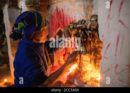 Una donna pellegrina a Boudhanath a Kathmandu, Nepal, suonando una campana al santuario. Foto Stock