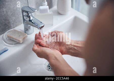 Uomo che pulisce le mani sopra il lavandino Foto Stock
