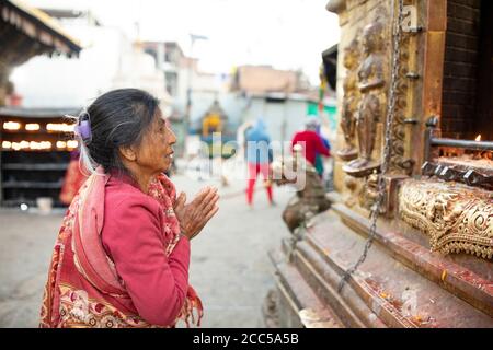 Donna che prega con le mani ripiegate in un santuario a Swayambhunath stupa Kathmandu, Nepal. Foto Stock