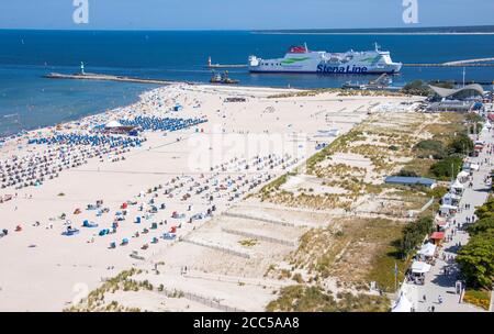 Rostock, Germania. 12 agosto 2020. Dietro l'ampia spiaggia sabbiosa di Warnemünde, il traghetto 'Mecklenburg-Vorpommern' della compagnia di navigazione Stena Line da Trelleborg (Svezia) viaggia attraverso il canale marittimo fino al porto dei traghetti di Rostock. Credit: Jens Büttner/dpa-Zentralbild/ZB/dpa/Alamy Live News Foto Stock