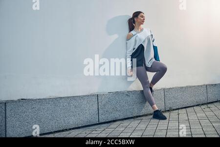 Donna stanca che si sta riprendendo dopo un intenso allenamento Foto Stock