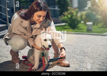 Donna felice con un gadget e un animale domestico Foto Stock