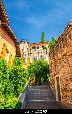 Scala scala di strada stretta tra pareti in pietra. Scalinata Castel S. Pietro che porta a Castel San Pietro nel centro storico di Verona, sfondo blu cielo, Regione Veneto, Italia settentrionale Foto Stock