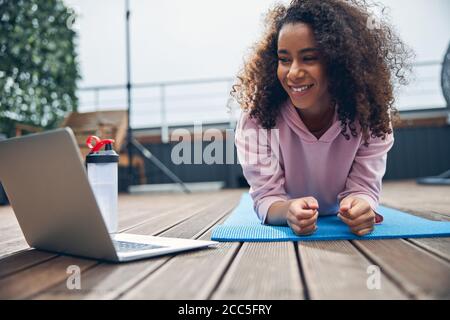 Bella signora con capelli ricci facendo esercizio fisico all'esterno su tetto Foto Stock