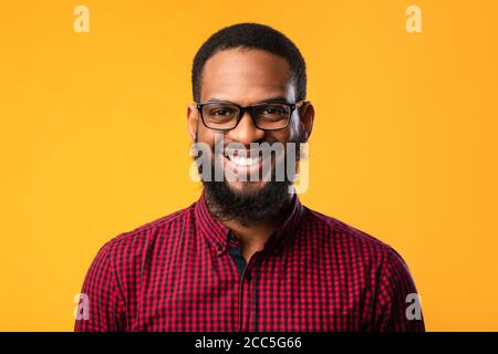 Sorridente afro uomo che posa su sfondo giallo Foto Stock