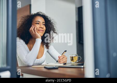 Bella donna afroamericana sognando con penna in mano Foto Stock