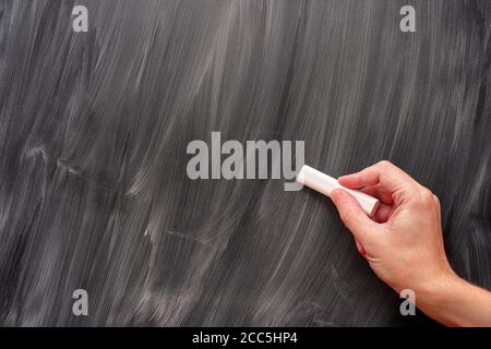 Persona che usa il gesso bianco su una lavagna. Primo piano. Foto Stock