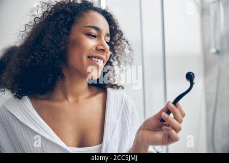 Allegra femmina con testa riccia che tiene un micro-ago Foto Stock