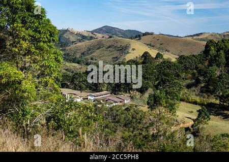 Un vicino ranch tra le montagne di Cunha come visto da una delle colline più alte della fattoria o Contemplario nel tardo pomeriggio cielo blu nuvoloso. Foto Stock