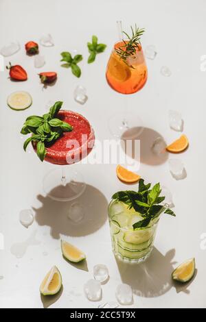 Popolari cocktail alcolici estivi al bar. Gin-tonic, Aperol Spritz e Margarita al basilico di fragole su fondo bianco chiaro, fuoco selettivo Foto Stock