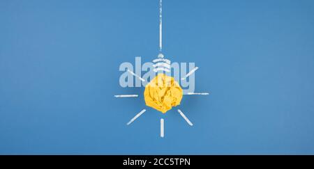 lampadina realizzata in carta gialla sbriciolati su sfondo blu, idea e concetto di innovazione Foto Stock