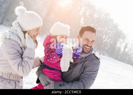 Felice famiglia e la loro piccola figlia godendo di una bella e. freddo giorno d'inverno Foto Stock