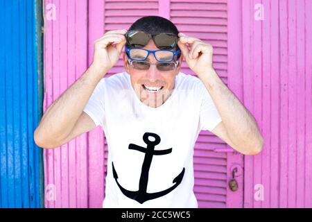 Piacevole attraente divertente ragazzo felice indossare camicia marinaio sentire fresco con tre pere di specs godere l'estate sul spiaggia su un luminoso e vivace rosa b Foto Stock