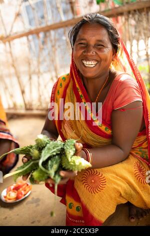 Una donna si siede nella sua cucina con zucca amara appena raccolta, prelevata dalla sua fattoria a Bihar, India, Asia meridionale. Foto Stock