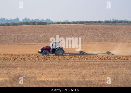 Trattore che arava un campo nel deserto di Negev, Israele fotografò a Kibbutz Magen Foto Stock