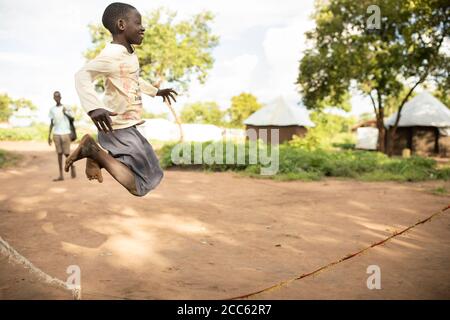 I bambini rifugiati sudanesi saltano la corda insieme nel campo profughi di Palabek, nel nord Uganda, Africa orientale. Foto Stock