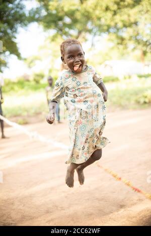 I bambini rifugiati sudanesi saltano la corda insieme nel campo profughi di Palabek, nel nord Uganda, Africa orientale. Foto Stock