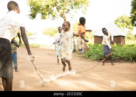 I bambini rifugiati sudanesi saltano la corda insieme nel campo profughi di Palabek, nel nord Uganda, Africa orientale. Foto Stock