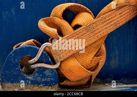 primo piano di una robusta cinghia in nylon fissata a una macchina blu con gancio in acciaio Foto Stock