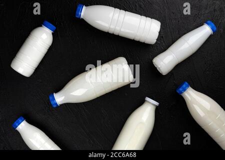 Confezionamento prodotti caseari, bottiglie e bicchieri con latte su sfondo nero, vista dall'alto Foto Stock