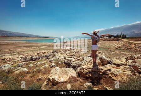 Donna felice con le mani alzate in piedi vicino ai laghi e godere di una vista incredibile. Splendido paesaggio di pietra nel mezzo della valle. Viaggia lungo il Libano Foto Stock