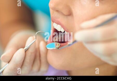Mani di dentista che esaminano pazienti di donna dente in clinica dentale, primo piano Foto Stock