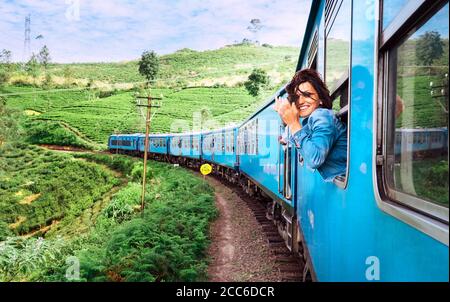 Sorridenti donna guarda fuori dalla finestra il viaggio in treno per la maggior parte dei treni pittoresca strada in Sri Lanka Foto Stock