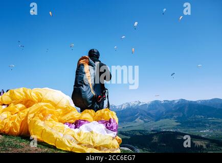 Paraplanner in attrezzatura completa per il volo guarda a salire un altro paraplanes in cielo Foto Stock