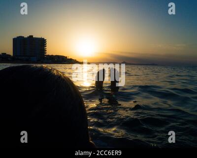 donna si rilassa in mare guardando il tramonto Foto Stock