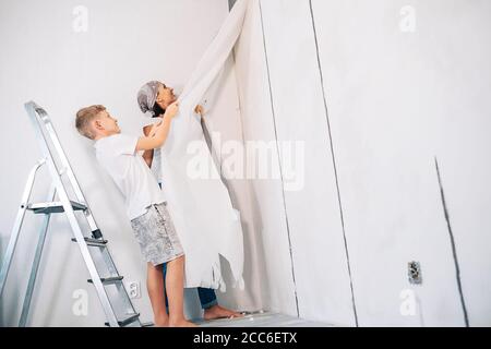 Madre e figlio prendono insieme gli sfondi e preparano la stanza per lavori di ristrutturazione Foto Stock