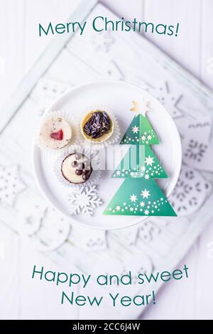 Buon Natale, felice e dolce anno nuovo. Biglietto d'auguri. Albero di Natale verde, caramelle fatte in casa, ornamenti di natale in vassoio bianco su un legno bianco Foto Stock