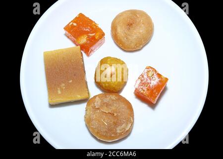 Dolci indiani serviti in piatto bianco. Halwa, badusha, ghee mysore pak, laddu in piastra decorativa, Foto Stock