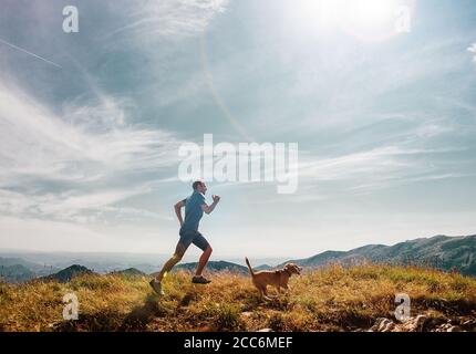 L'uomo corre con il suo cane di aquila sulla cima della montagna Foto Stock