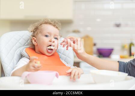 La mamma alimenta il bambino con un cucchiaio. Foto Stock