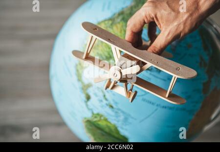 Modello in legno di aeroplano d'epoca vola vicino al globo terrestre. Concetto di viaggio in tutto il mondo Foto Stock