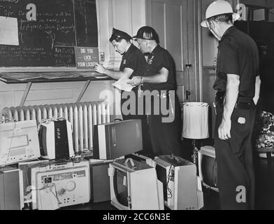 Gli ufficiali di polizia Tom McMahon, David Ablett e Robert Fales documentano gli oggetti rubati confiscati dopo la notte dei saccheggi a causa della sparatoria fatale di Teen James Powell da parte del funzionario di polizia Lt. Thomas Gilligan, Brooklyn, New York, USA, John Bottega, World Telegram & Sun, 22 luglio 1964 Foto Stock