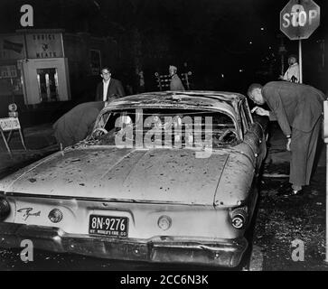 Investigatore che esamina l'automobile bruciata fuori della polizia dopo notte di saccheggi dovuto sparare mortale di Teen James Powell dall'ufficiale della polizia Lt. Thomas Gilligan, Herkimer Street e Nostrand Avenue, Brooklyn, New York, USA, Stanley Wolfson, World Telegram & Sun, luglio 1964 Foto Stock