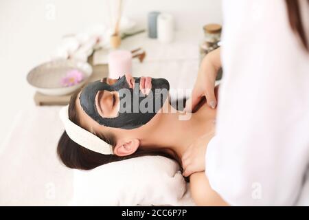 Centro benessere. Bella donna divertente con una maschera di argilla sul viso. Foto Stock