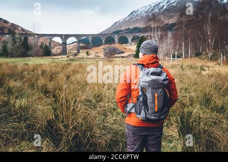 Escursione, passeggiata con zaino, stile di vita attivo concept immagine. Uomo viaggiatore cammina neaar famoso Glenfinnan viadukt in Scozia Foto Stock